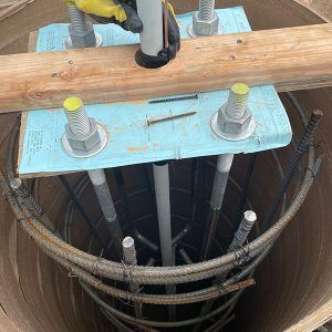Construction foundation with rebar cage and anchor bolts inside a round concrete shaft