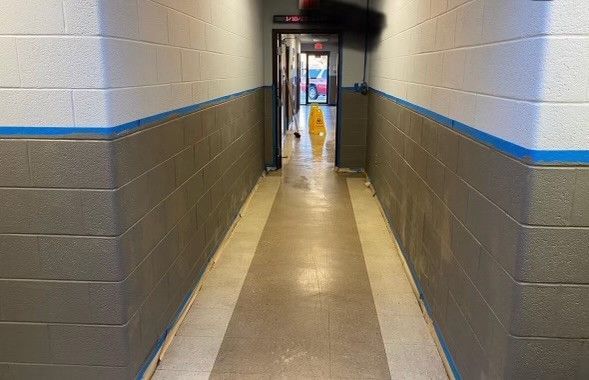 a long hallway with brick walls and a yellow mop on the floor .