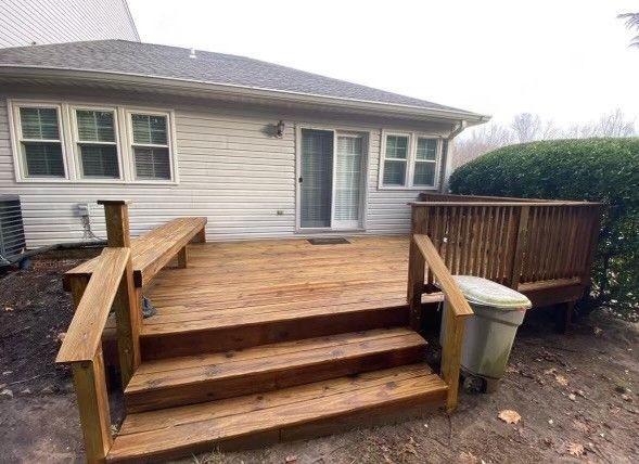 a wooden deck with stairs and a trash can in front of a house .
