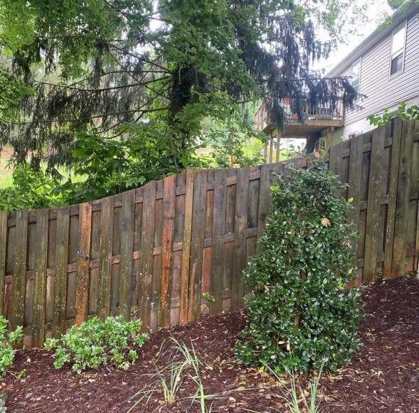 a wooden fence is surrounded by trees and bushes in front of a house .