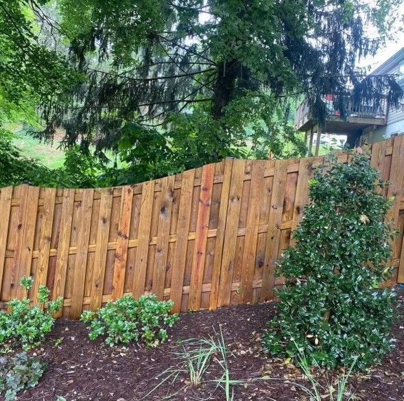 a wooden fence is surrounded by trees and bushes in a yard .