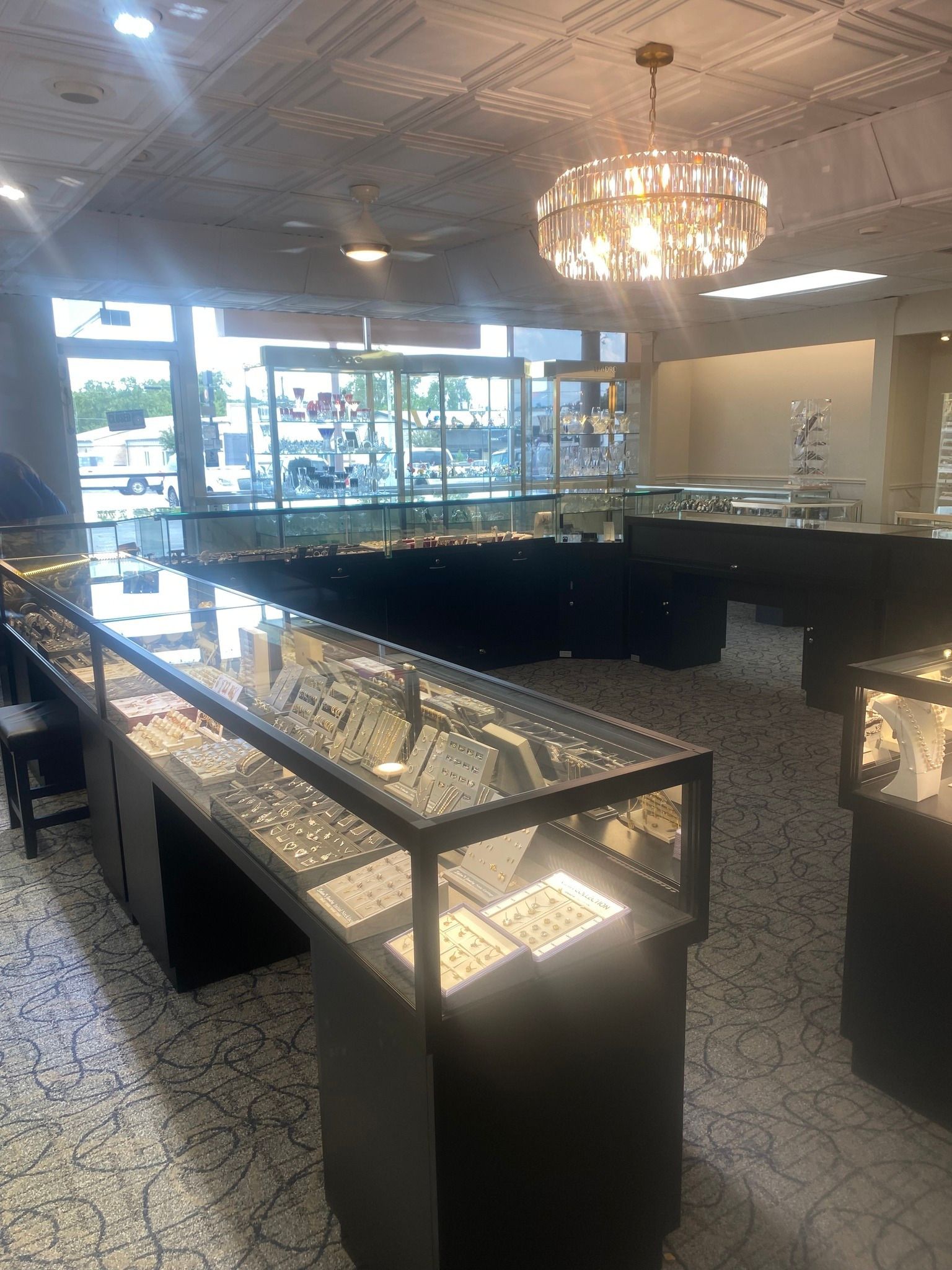 Jewelry store interior with display cases, overhead lighting, and view of the outside.