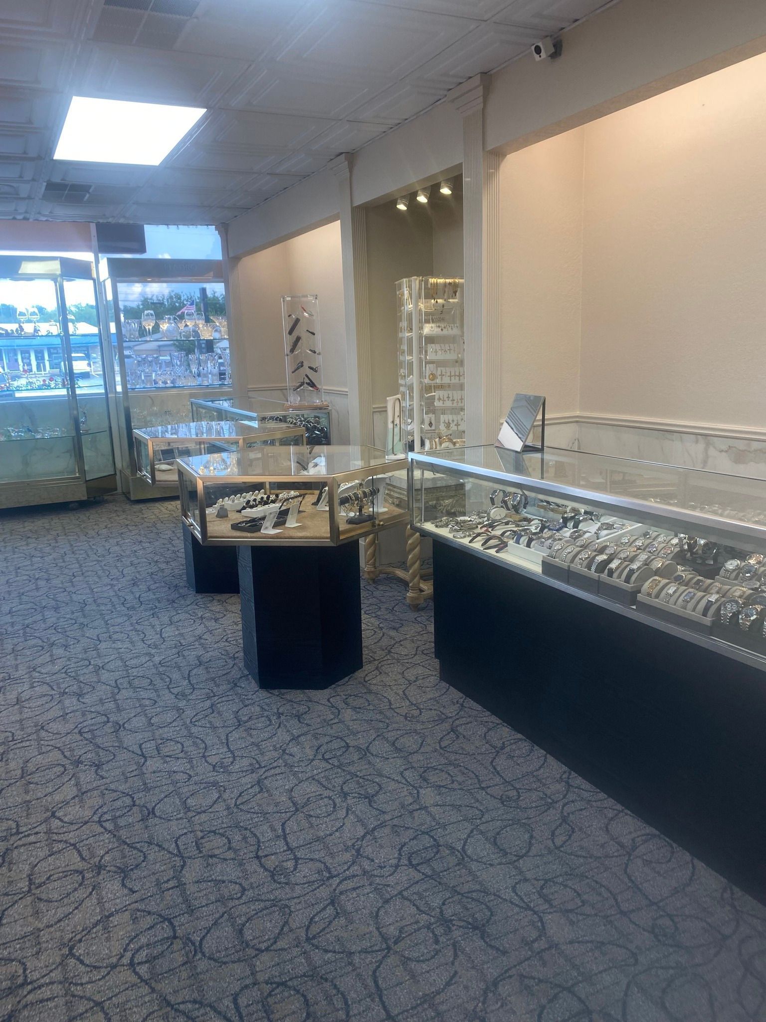 Jewelry store interior with display cases full of jewelry, on patterned carpet.