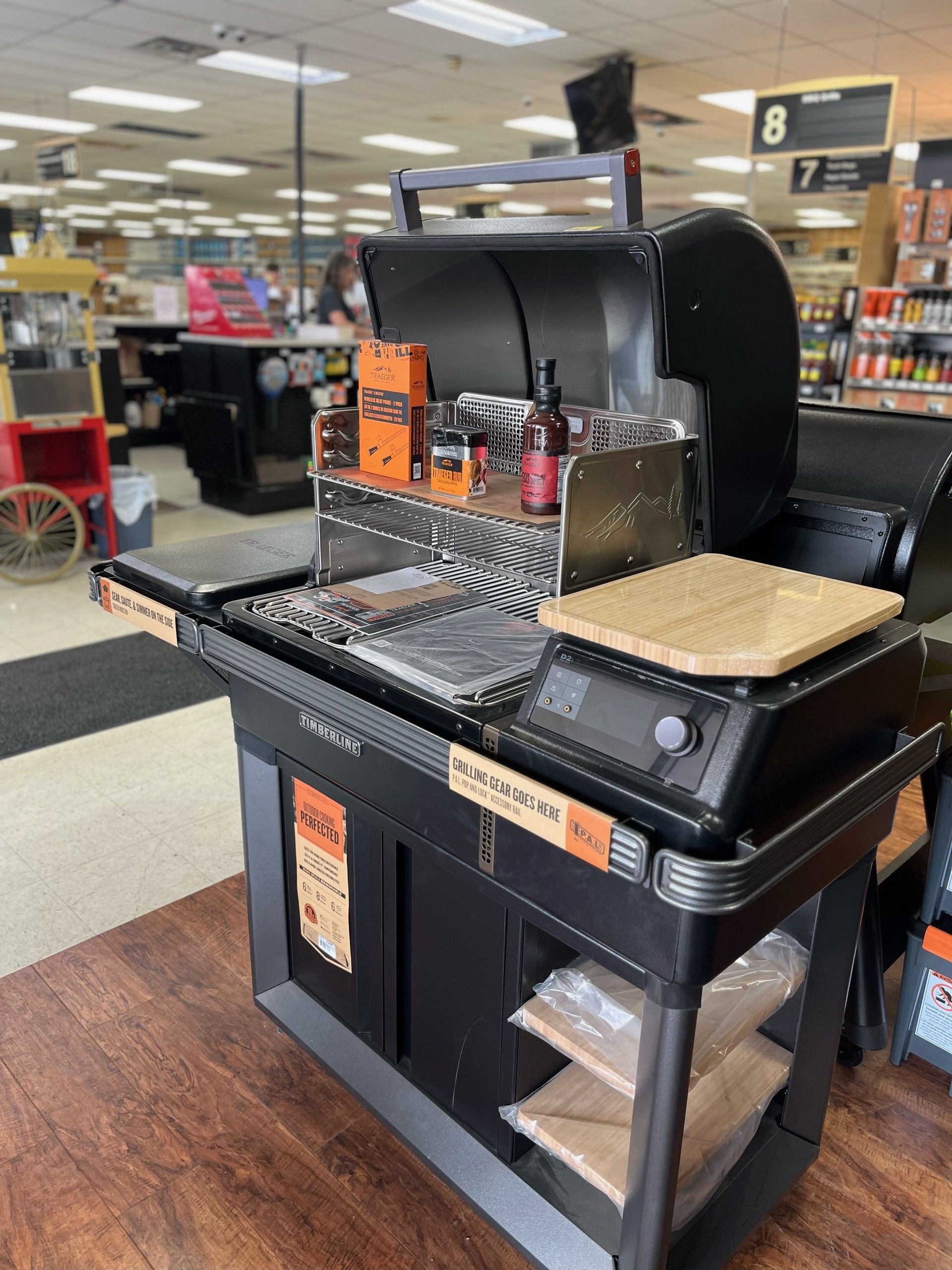 A black grill is sitting on a wooden floor in a store.