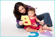 Mother on floor playing with child using large letters