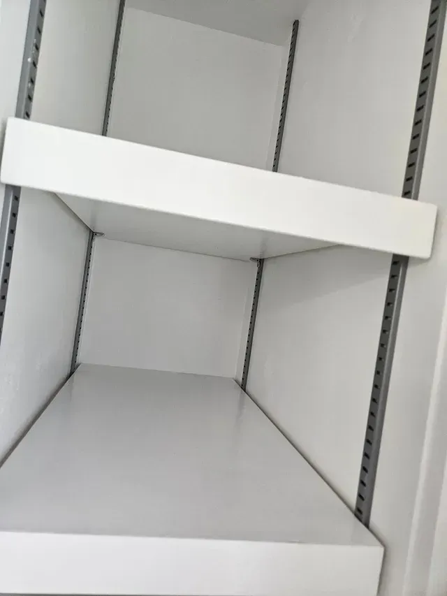 Empty white store shelf with a tilted divider panel and metal side rails