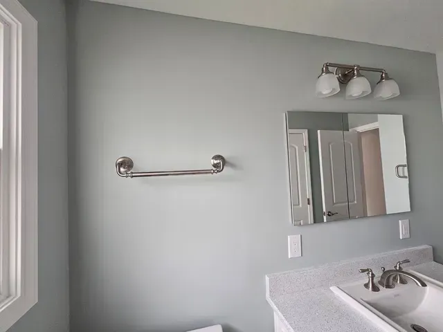 Bathroom vanity with mirror, light fixture, towel bar, and gray walls