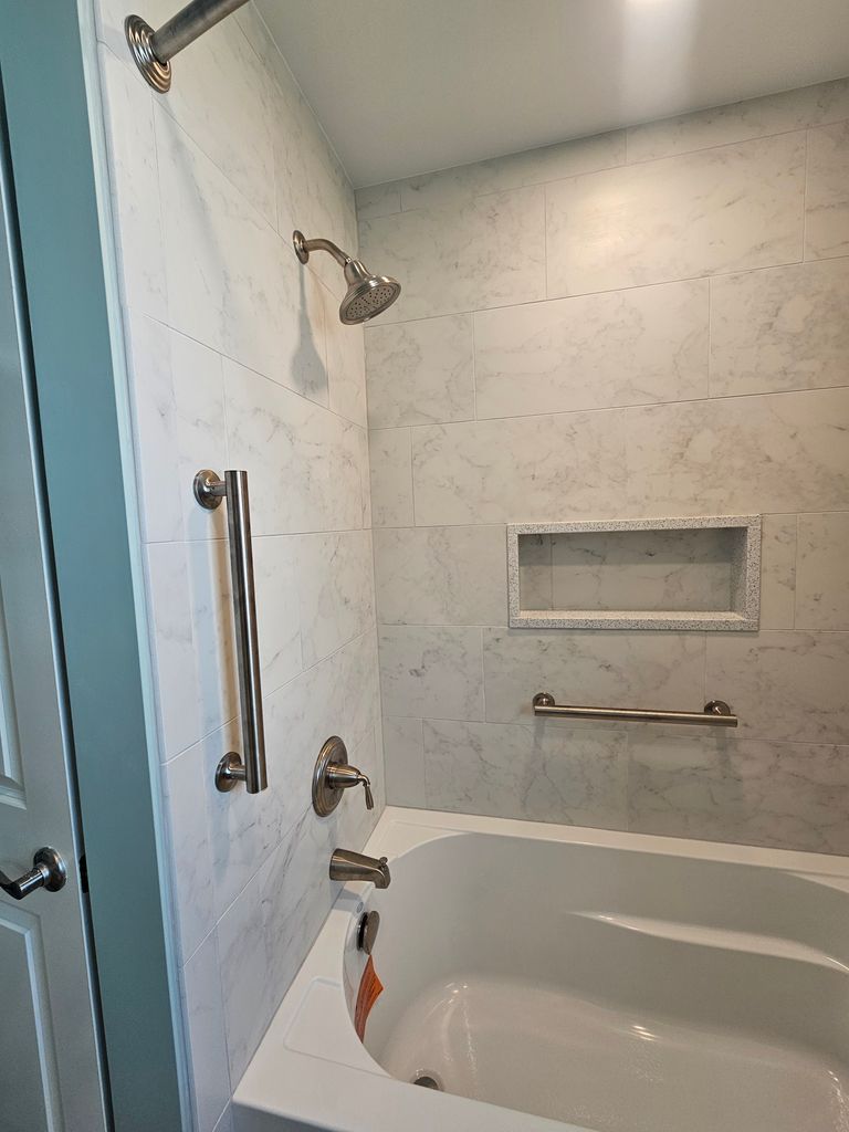 Accessible bathroom with walk-in shower, grab bars, and bathtub under a tiled wall.