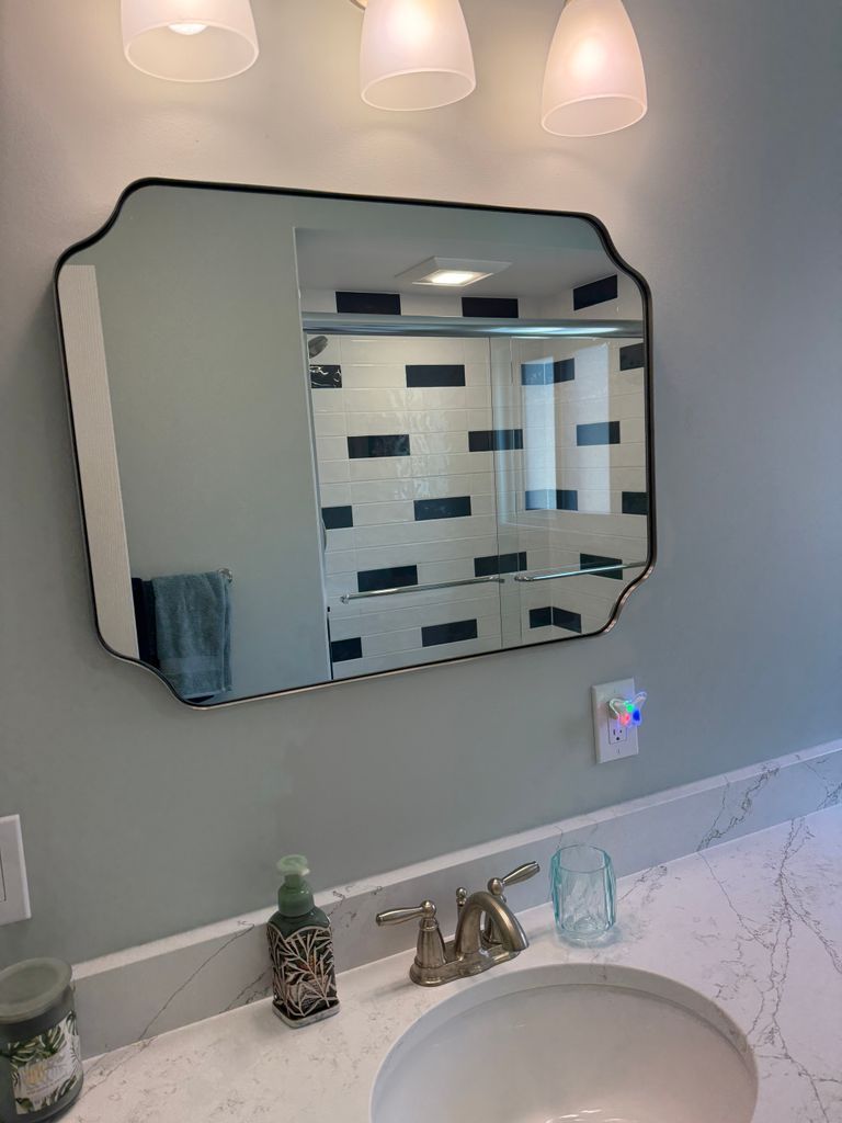 Bathroom vanity with octagonal mirror, marble counter, sink, and blue-gray walls
