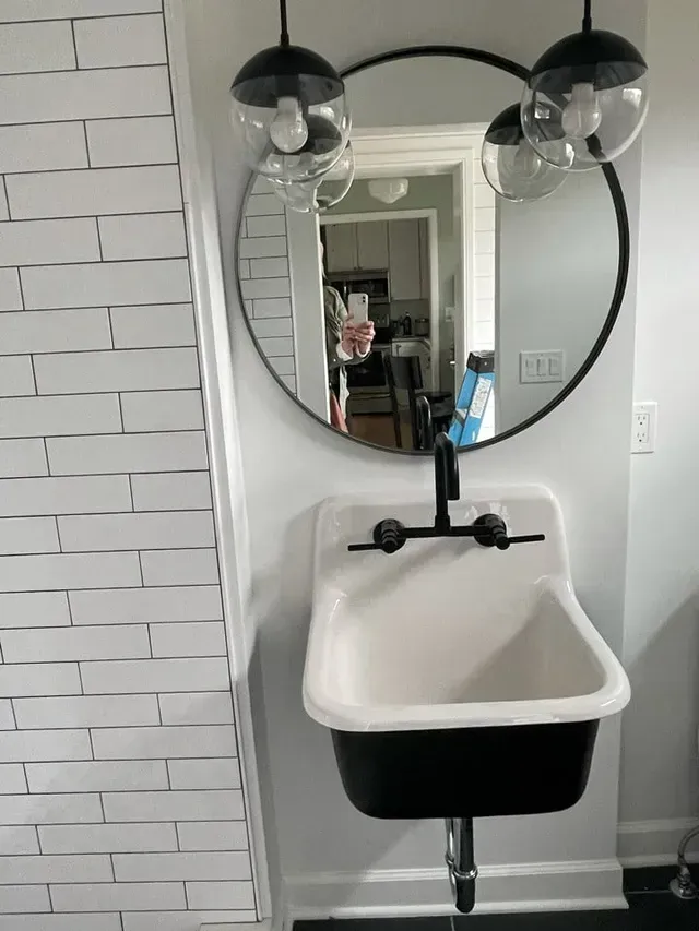 A bathroom sink with a round mirror above it.