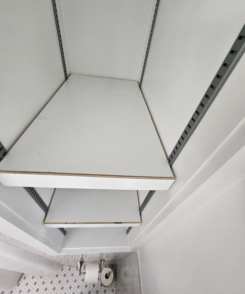 Empty white shelving unit viewed from below with metal side rails.