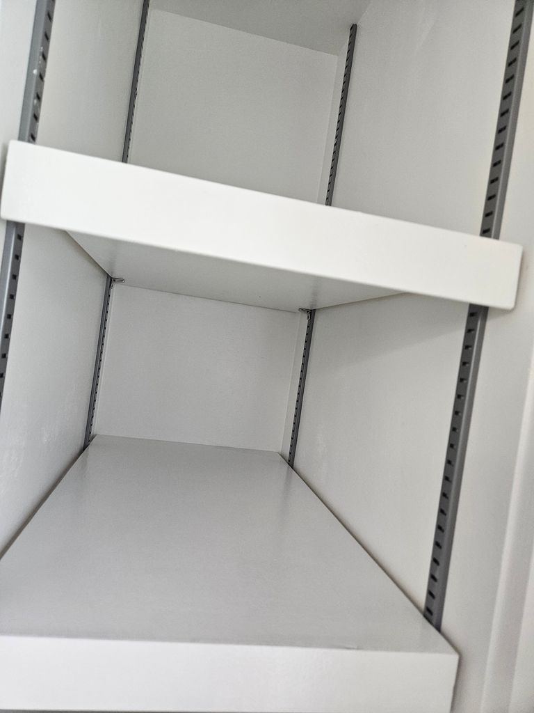 Empty white retail shelf with tilted divider panels inside a gray metal shelving unit