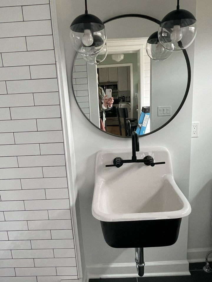 A bathroom sink with a round mirror above it.