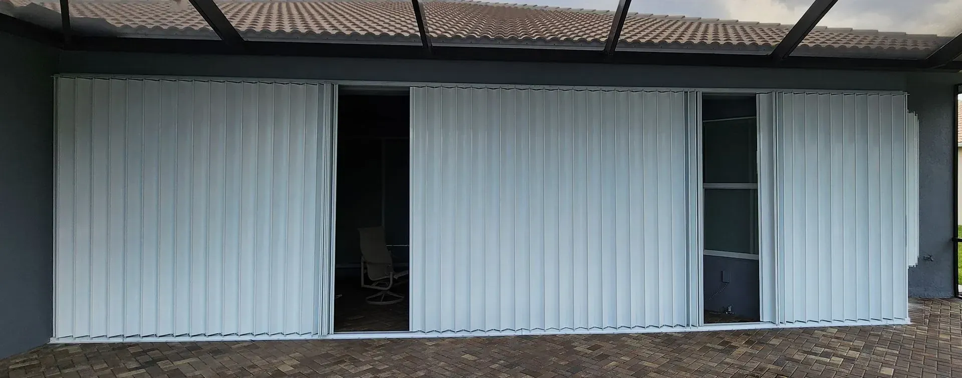 White corrugated sliding doors partially open on a gray building, under a dark roof.