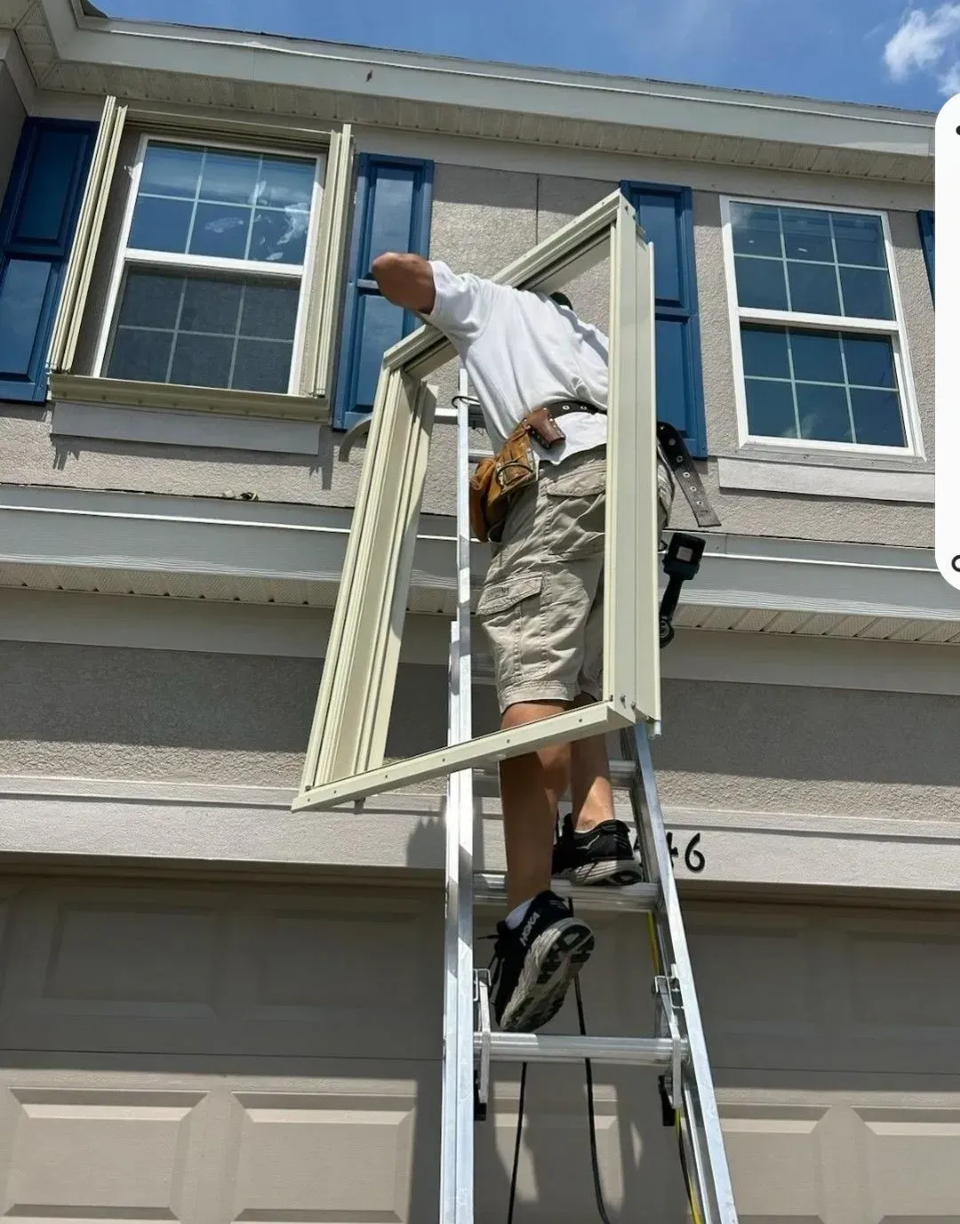 Person on ladder, installing a window in a two-story house.