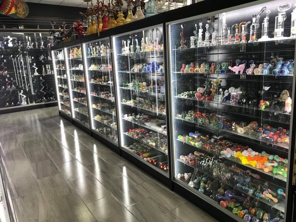 Inside a shop, glass pipes and hookahs displayed in illuminated cabinets.