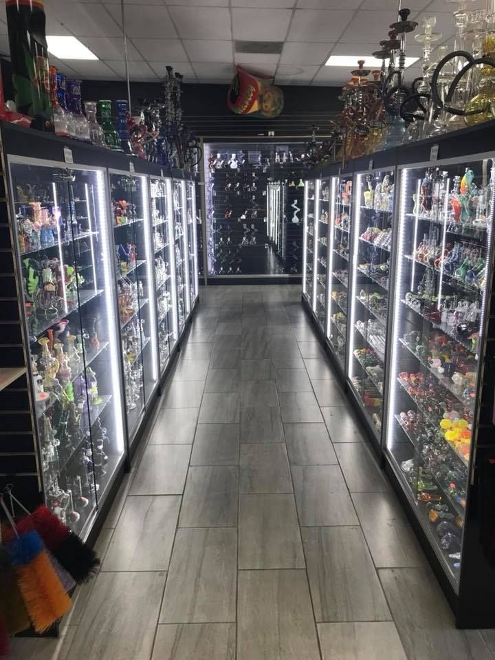 Rows of glass pipes in lit display cases at a smoke shop.
