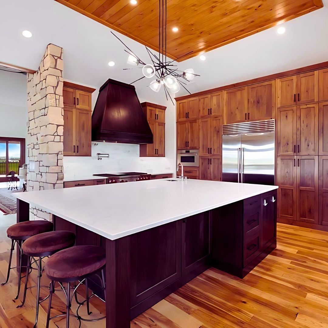 Spacious kitchen with dark cabinetry, a white countertop island, and a light fixture.