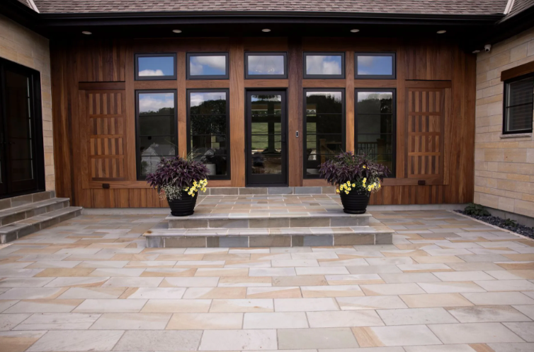 Patio with wooden doors, windows, and planters. Stone steps lead to the entrance.
