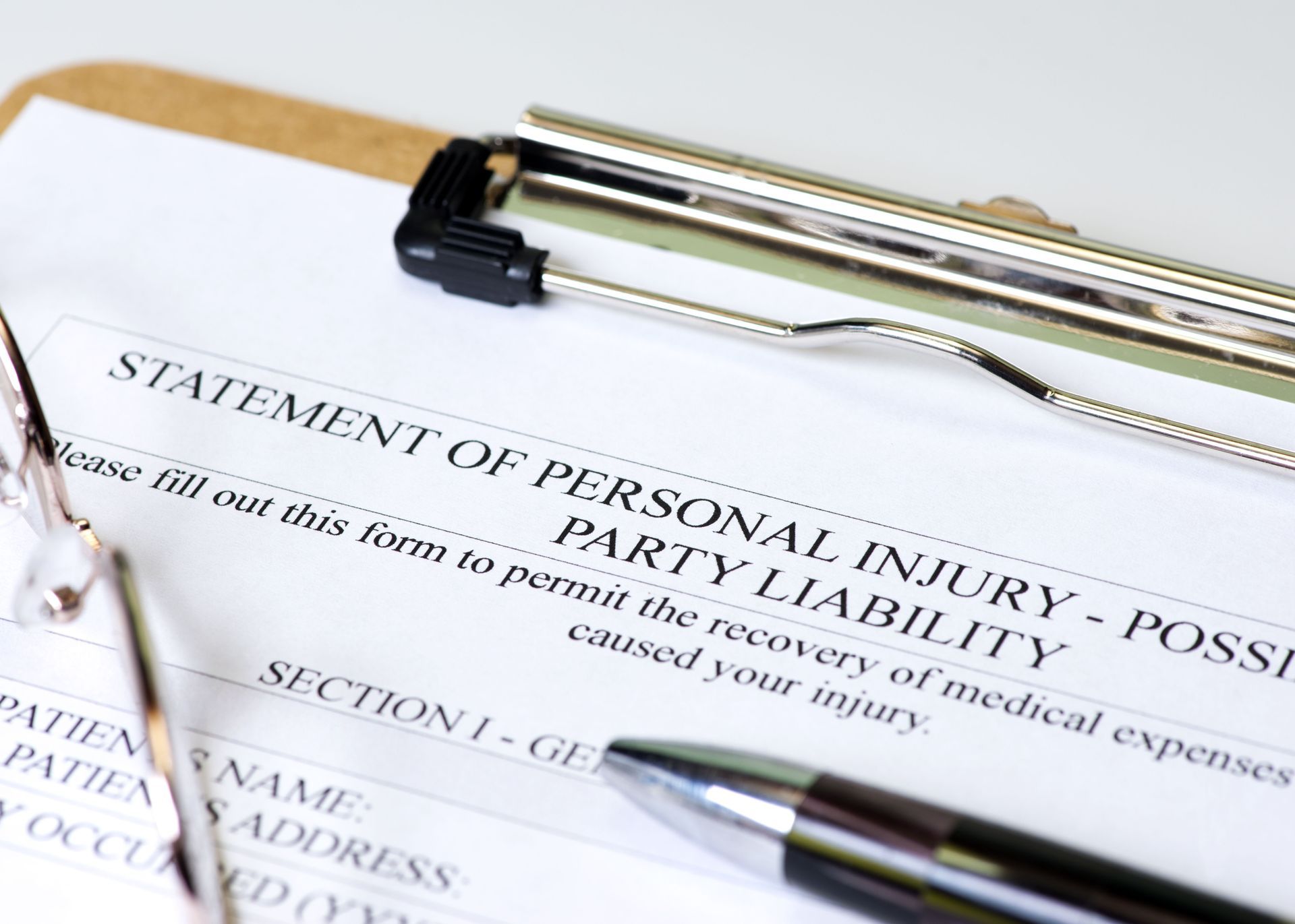 Close-up of a personal injury form on a clipboard with a pen and eyeglasses, ready to be filled out.