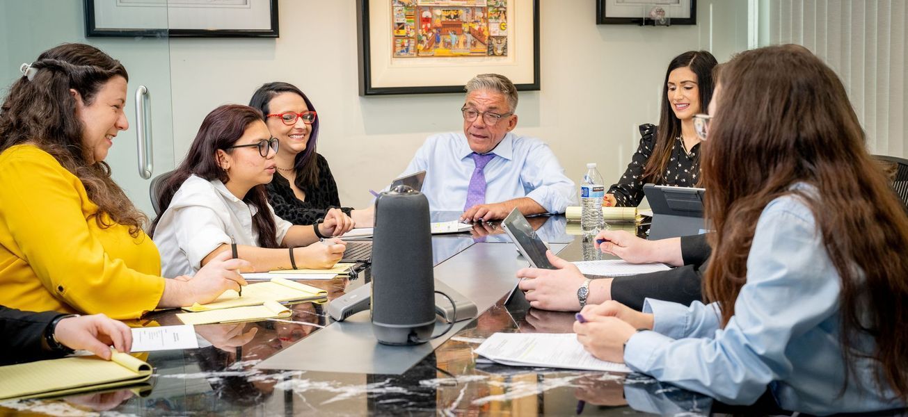 Group of people at a conference table, discussing papers. Office setting.
