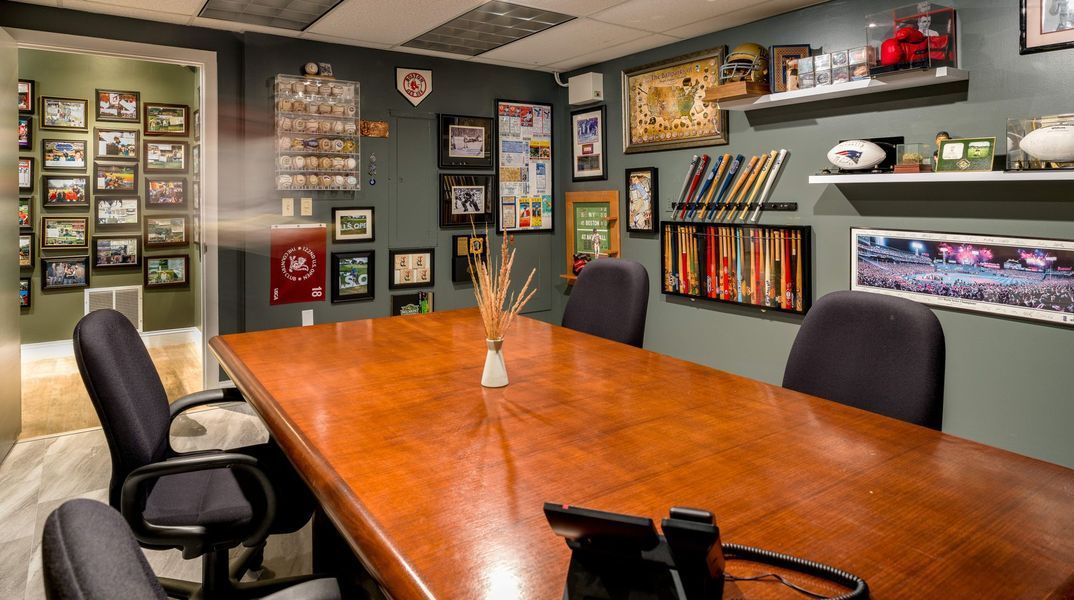 Meeting room with a large wooden table, chairs, and framed items on the walls.