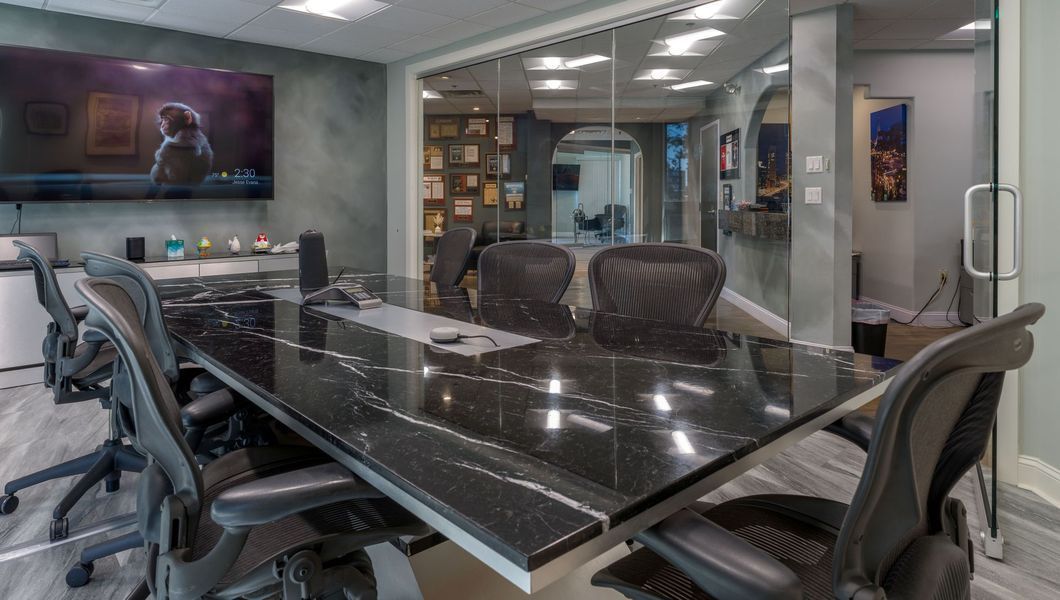 Conference room with black table, black chairs, TV, and glass wall.
