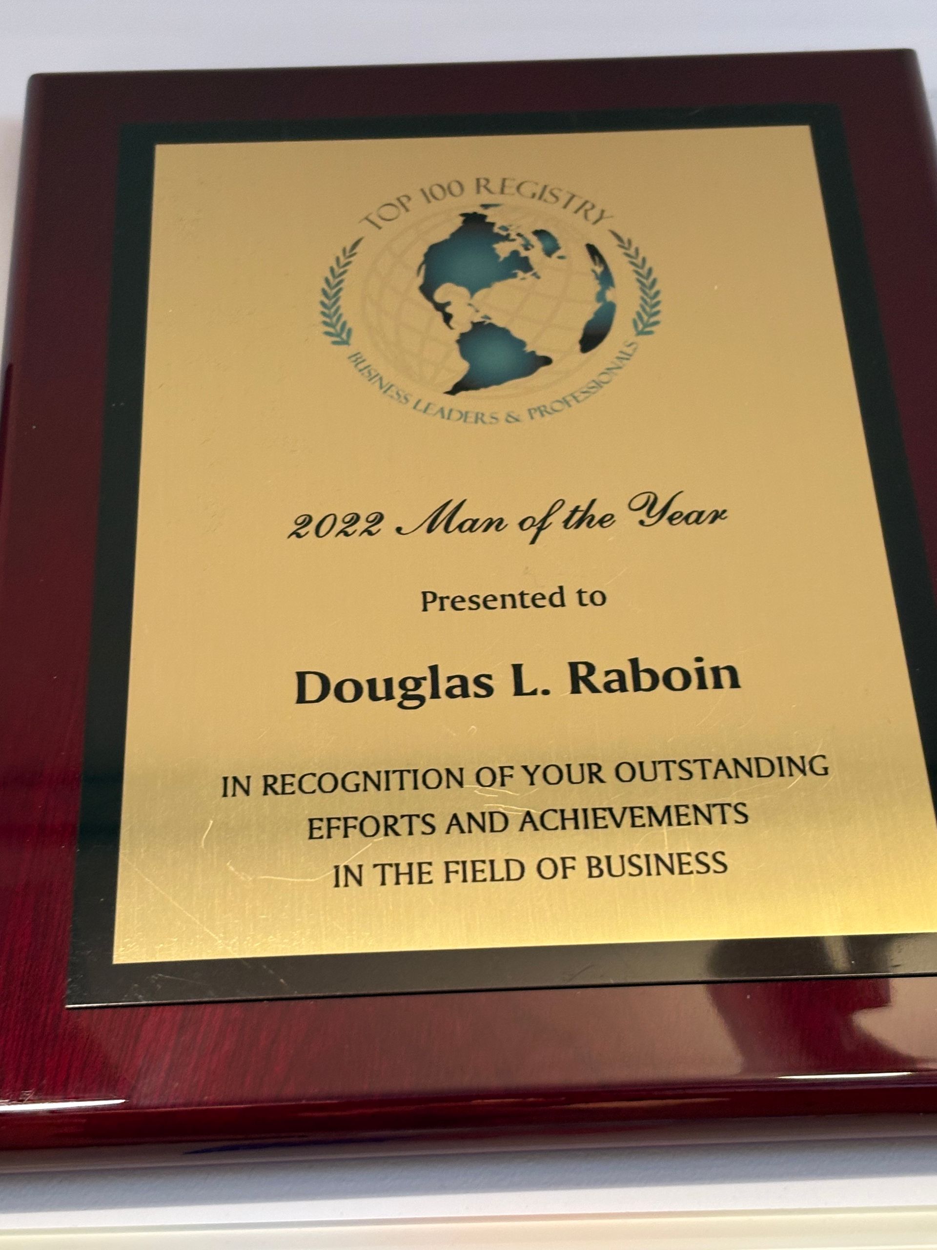 Plaque on dark wood stand honoring Douglas L. Raboin as 2022 Man of the Year for business achievements