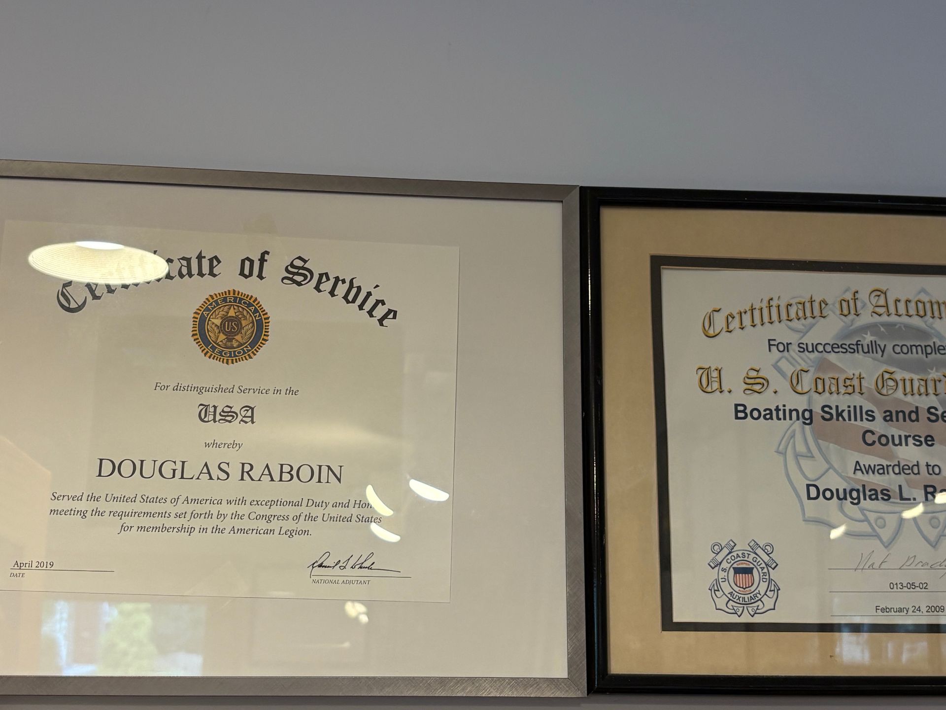 Framed service certificate and award certificate hanging side by side on a wall.