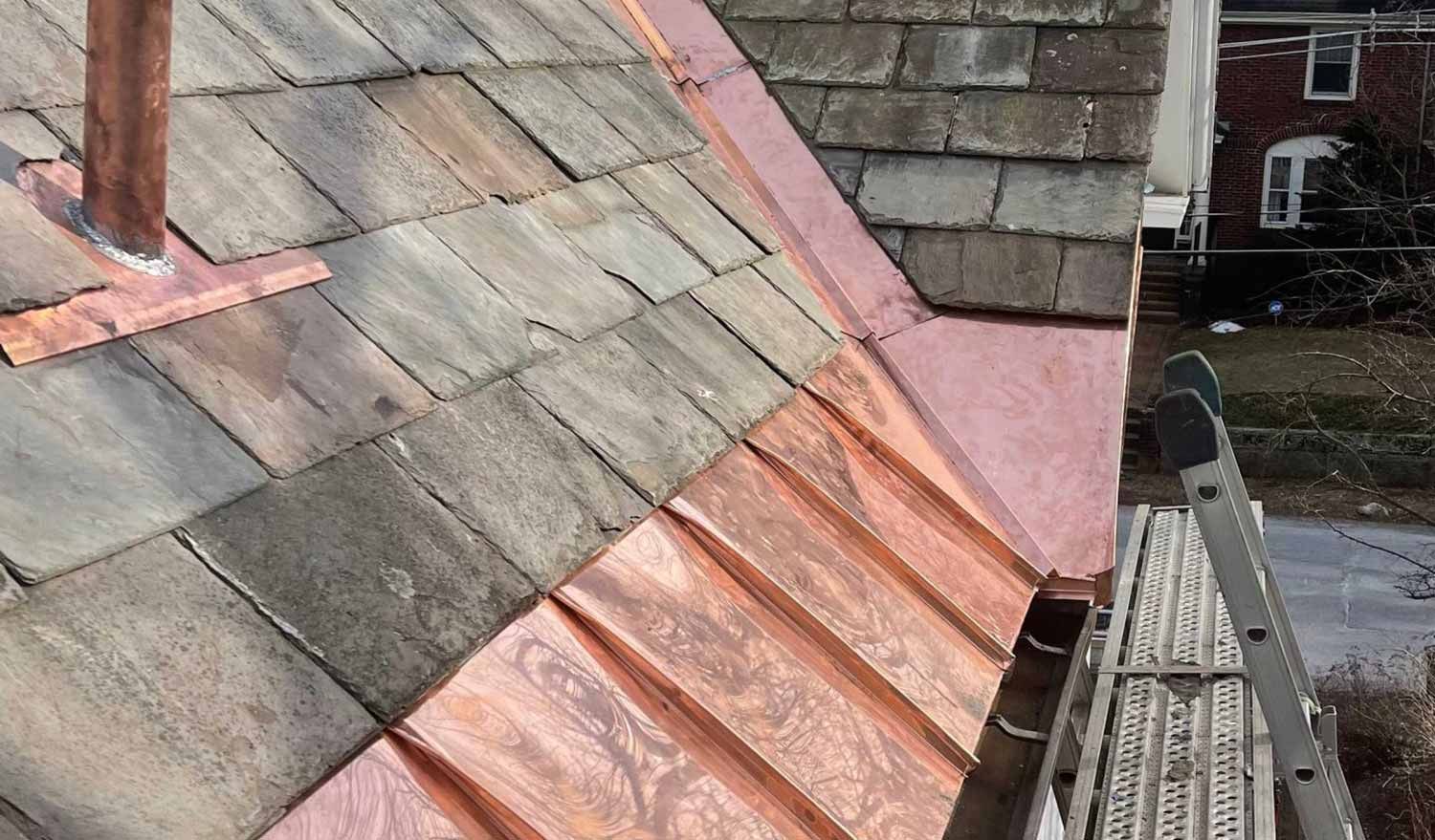 Slate and copper roof with a scaffolding platform along the edge of a building.