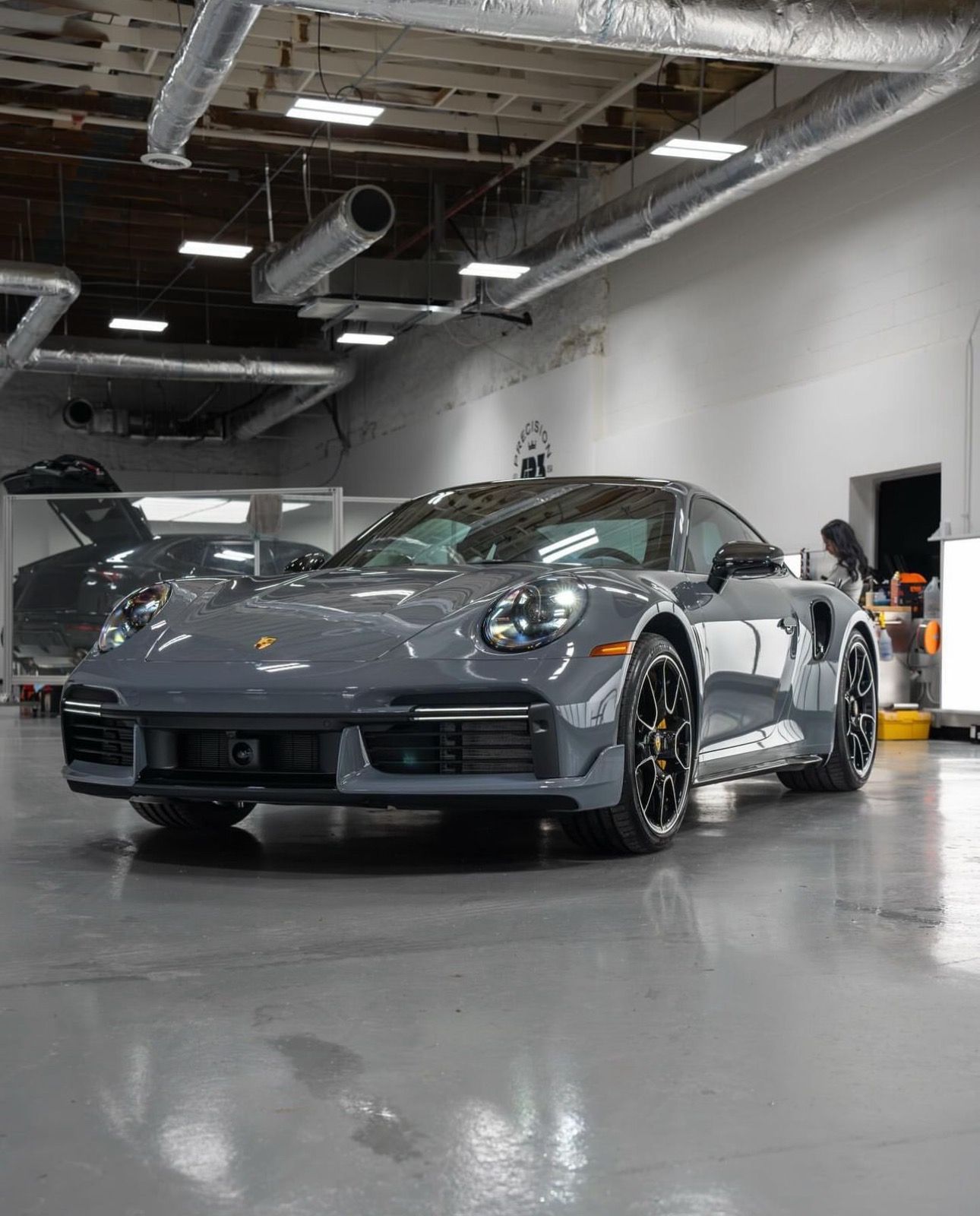 Gray Porsche sports car parked inside a well-lit garage.