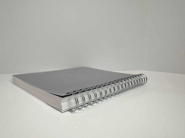Silver spiral notebook resting on a white surface.