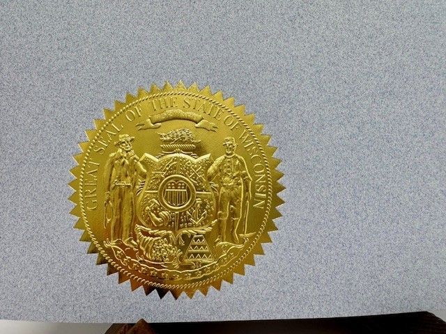 Gold embossed Wisconsin state seal on gray background.