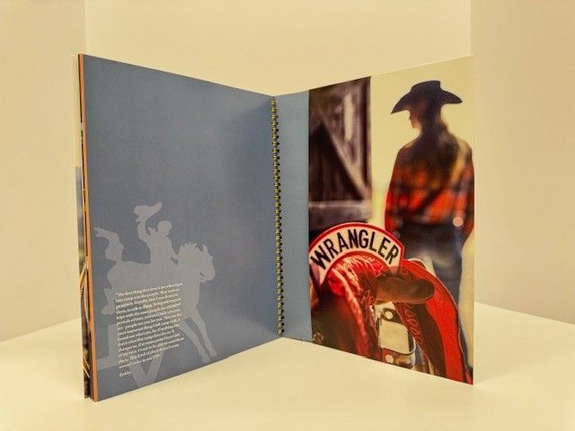 Open book with Western theme. Red Wrangler saddle and cowboy in background, blue page with silhouette.