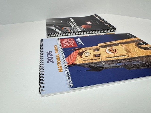 Two spiral-bound 2025 and 2026 calendars. One is titled 
