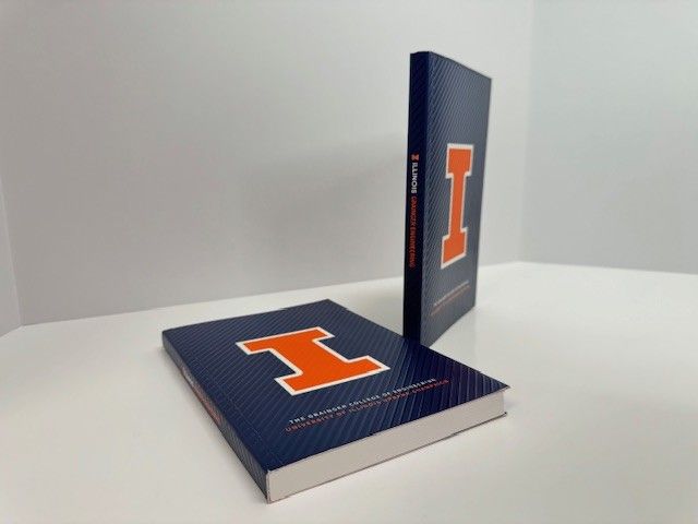 Two books: one flat, one standing, both with a blue cover and orange 