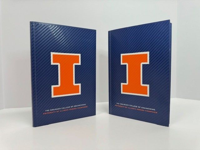 Two books with the University of Illinois logo on the cover. Blue background, orange 