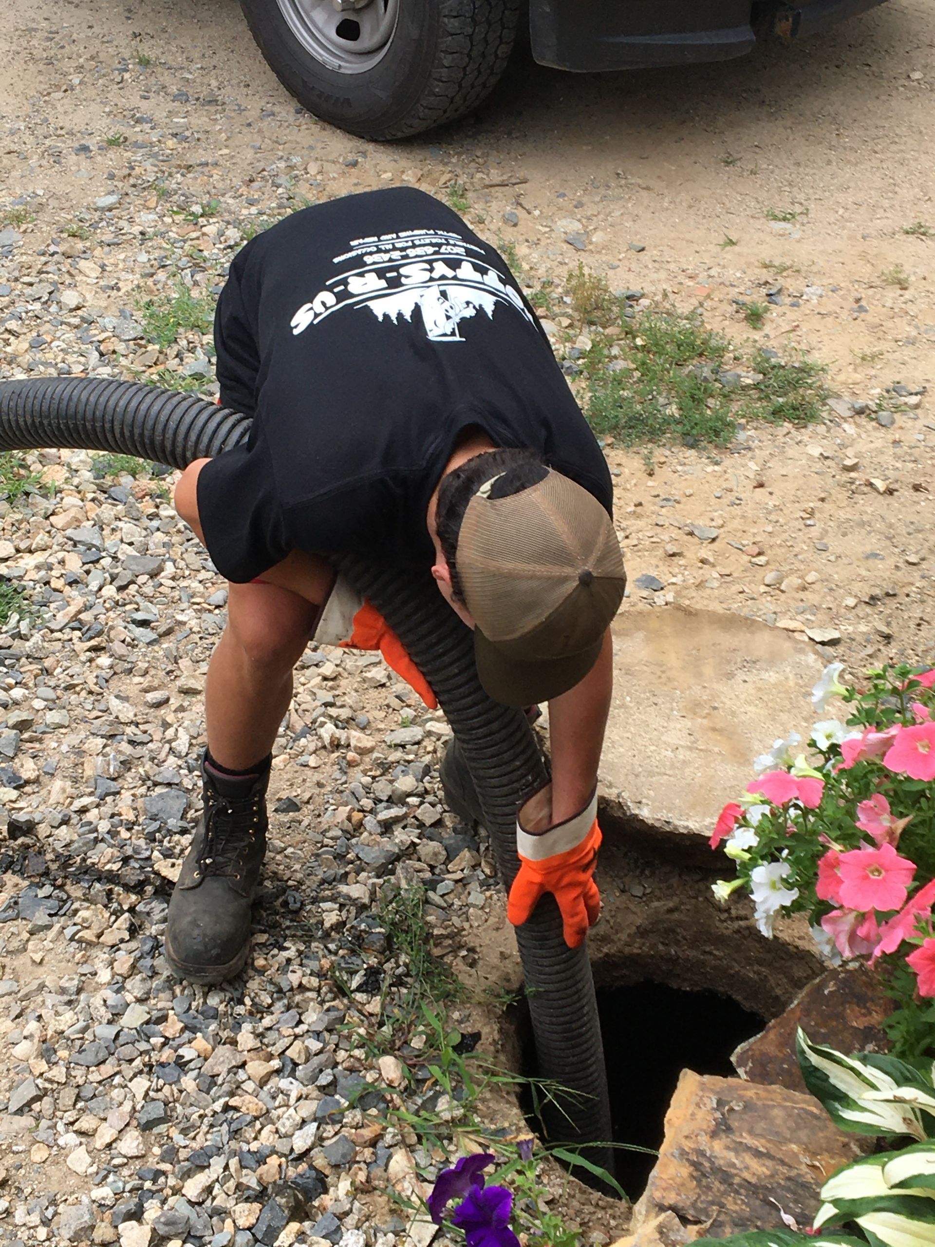 A man is using a hose to pump water into a drain.