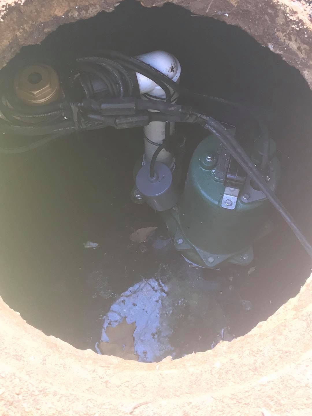 A green pump is sitting in the middle of a hole in the ground.