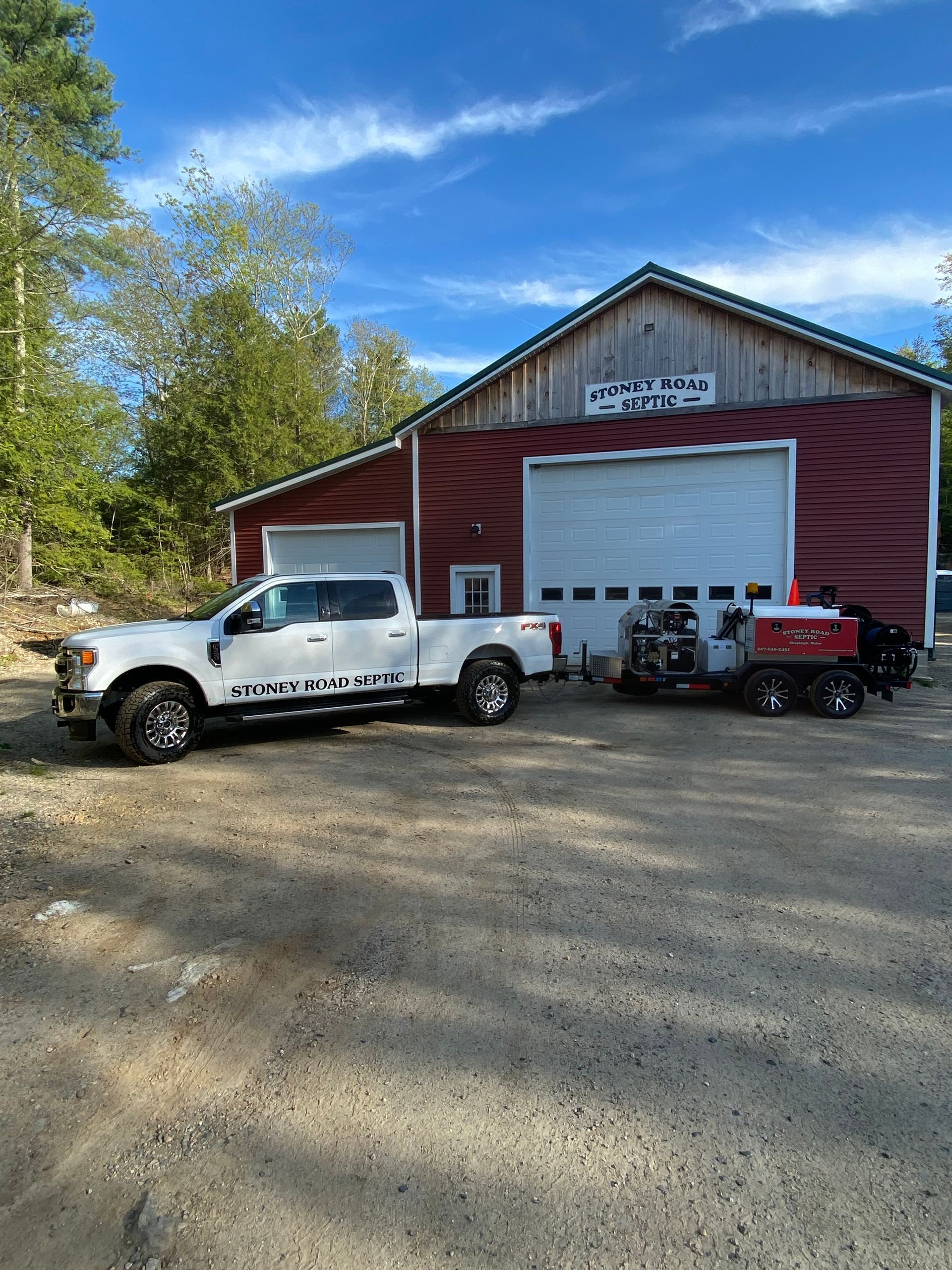 A white truck is parked in front of a red garage.
