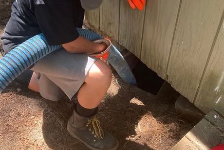 A man is using a hose to clean a hole in a wall.