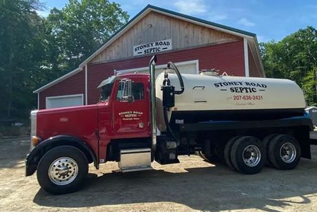 A septic truck is parked in front of a red building.