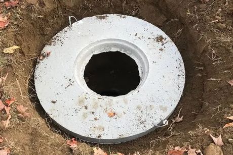 A concrete ring with a hole in the middle is sitting in the dirt.