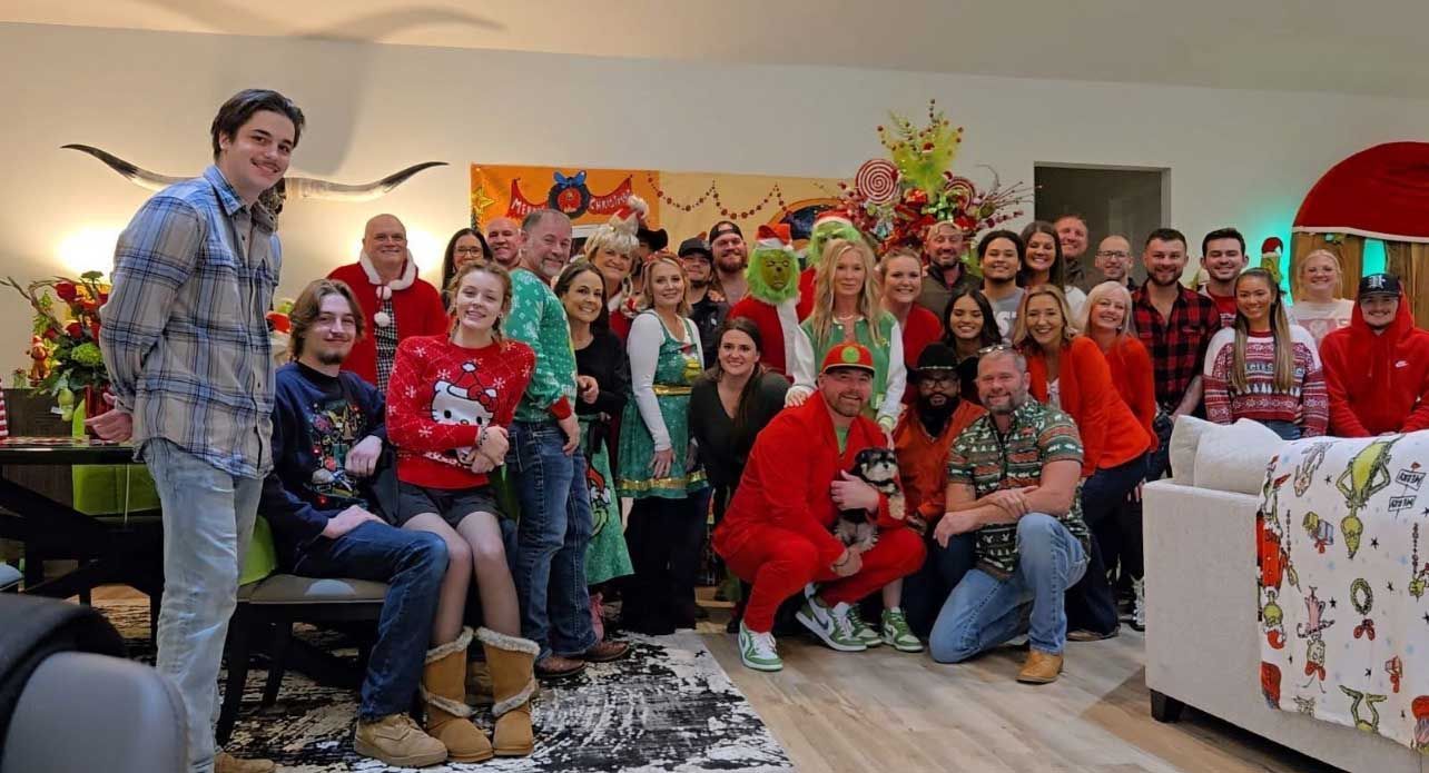 Group of people in festive attire posing indoors with Christmas decorations.