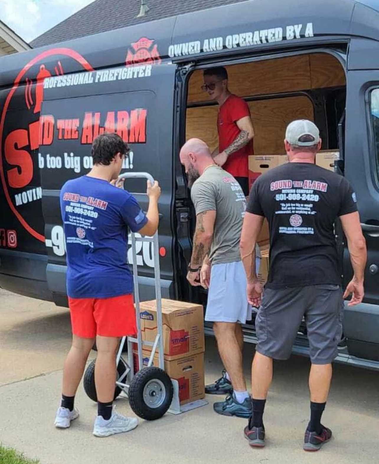 Movers loading boxes into a black van labeled 