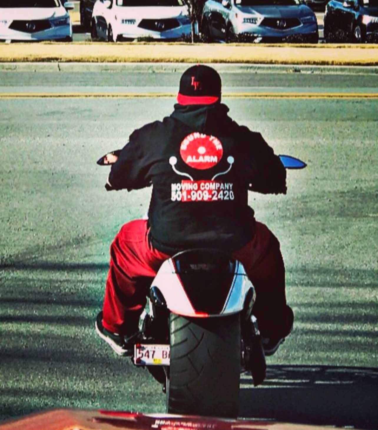Person on motorcycle, back view, wearing black hoodie with 