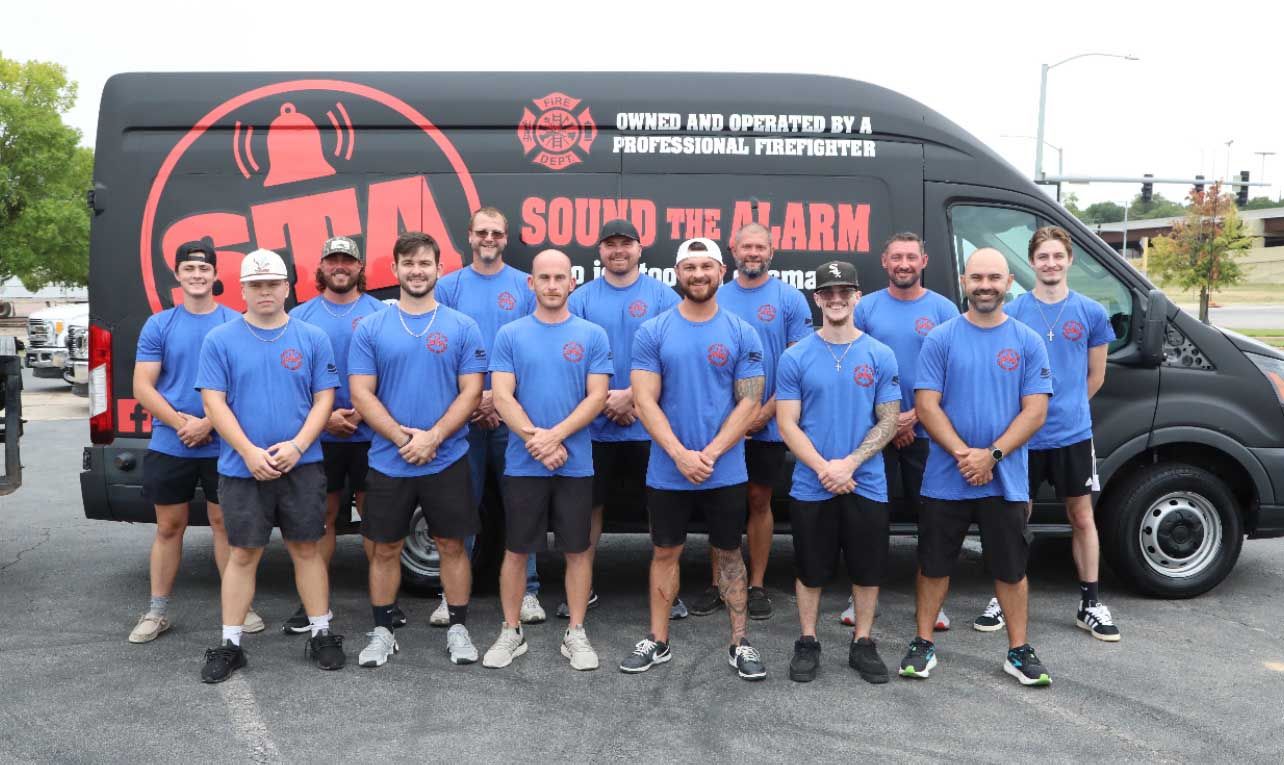 Group of men in blue shirts standing in front of a van with a company logo 