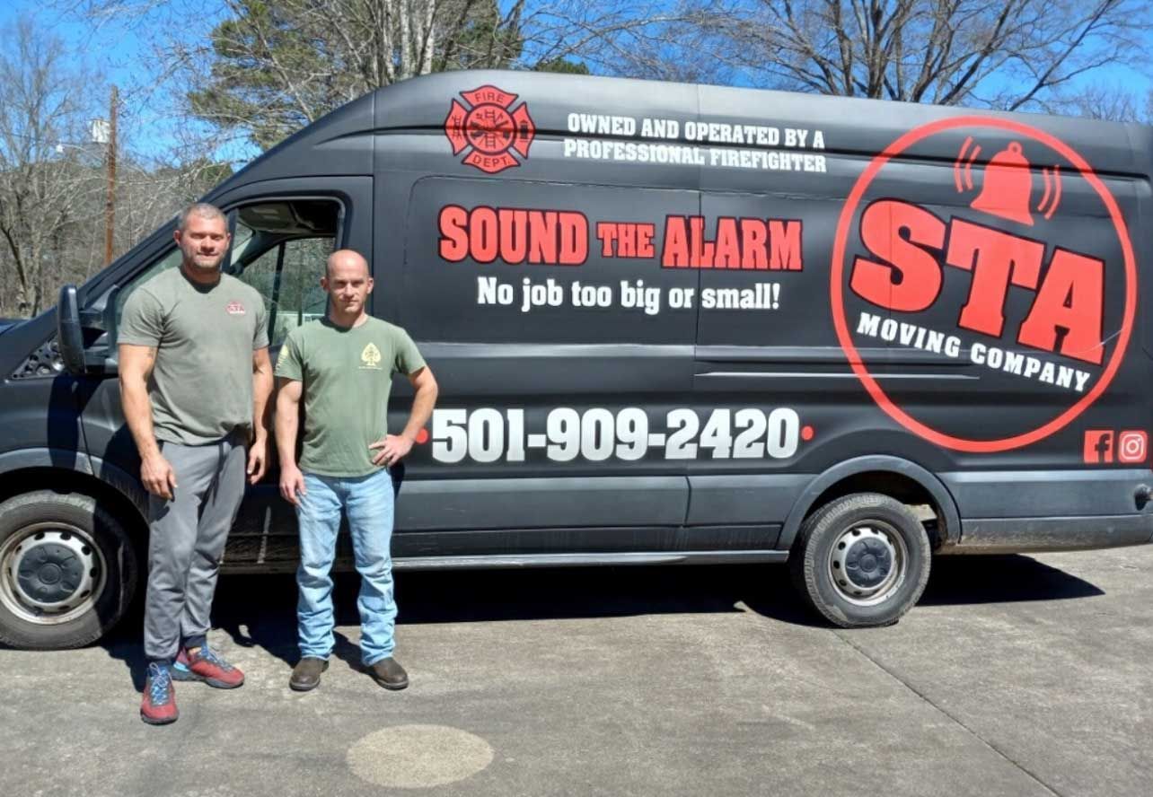 Two men standing next to a black van with 