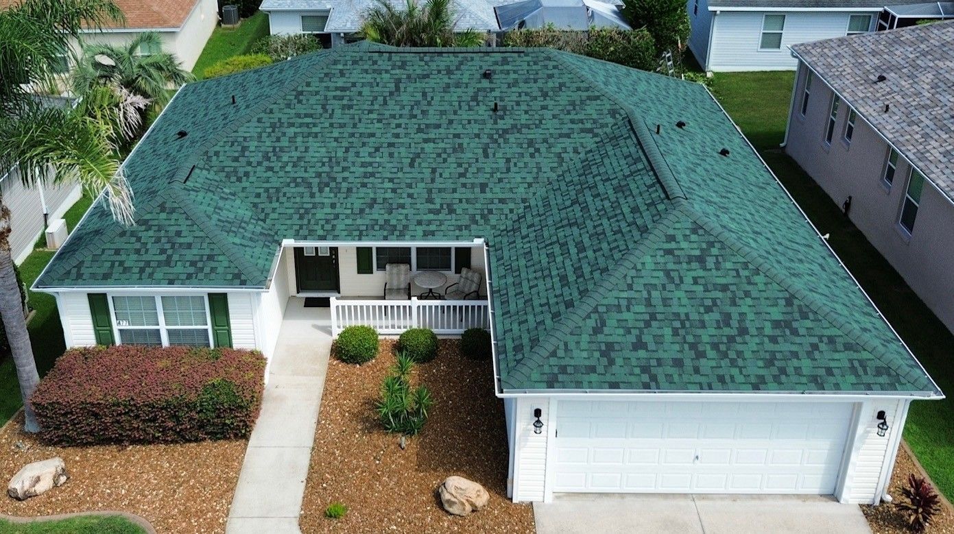 Suburban white house with gray roof, garage, front porch, and well-kept lawn under a blue sky