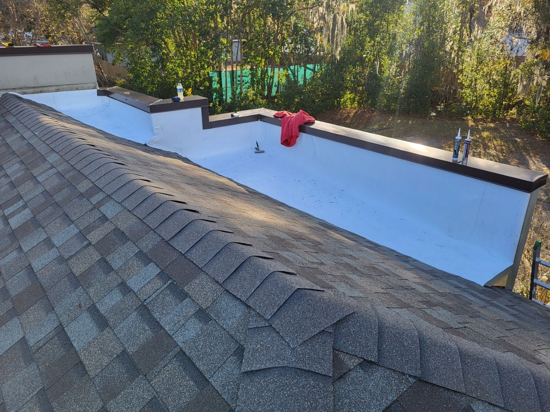 Rooftop with gray shingles and a white flat surface, featuring a red fire hydrant near the center.